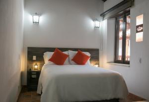 1 dormitorio con 1 cama blanca grande con almohadas rojas en Getsemani Cartagena Hotel, en Cartagena de Indias