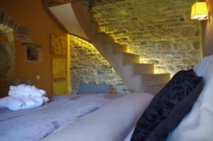 a bedroom with two beds and a stone wall at Le Mas de Laché in Caylus