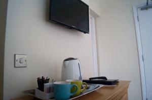 a table with cups and a tv on a wall at The Arun View Inn in Littlehampton