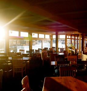 um restaurante com mesas e cadeiras e o sol a brilhar através das janelas em The Arun View Inn em Littlehampton