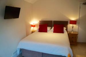 a bedroom with a bed with red pillows and a tv at The Arun View Inn in Littlehampton