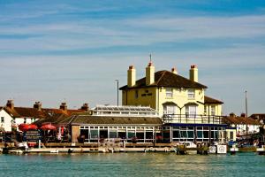 um grande edifício sobre a água ao lado de um porto em The Arun View Inn em Littlehampton