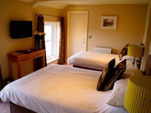 um quarto de hotel com duas camas e uma televisão em The Arun View Inn em Littlehampton