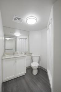a bathroom with a toilet and a sink and a mirror at Residence & Conference Centre - Toronto in Toronto