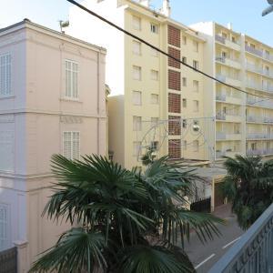 カンヌにあるViva Riviera Residence Palazzio Cannesのヤシの木が立ち並ぶ建物の前のバルコニー