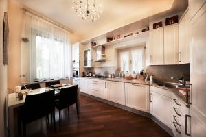 a kitchen with white cabinets and a table and a chandelier at Villa Castiglioni Luxury Apartment in Laglio