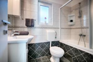 a bathroom with a toilet and a sink and a tub at Seafront Suites Maja in Vis +17 photos