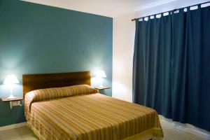 1 dormitorio con 1 cama con pared azul y cortinas azules en Brisas del Lago Apartamentos en Colón