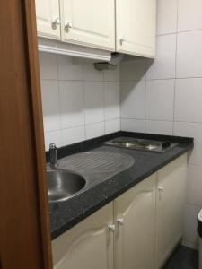 un bancone della cucina con lavello e armadietti bianchi di Seculo apartments a Porto