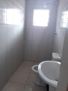 a white bathroom with a toilet and a sink at Hotel tenda 1 in Guarulhos