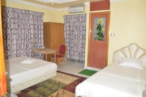 una habitación con dos camas y una mesa y una silla en Hotel Reyadha, en Cox's Bazar 20 fotos más
