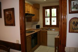 a kitchen with wooden cabinets and a sink and a microwave at San Antón in Benasque