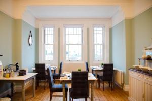 a dining room with tables and chairs and windows at The Carrick in Portrush