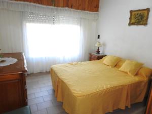 a bedroom with a bed with a yellow bedspread and a window at La Loberia - Las Grutas in Las Grutas