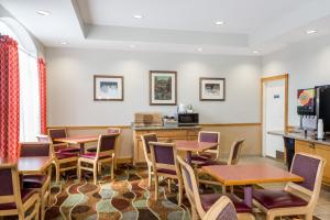 a waiting room with tables and chairs at Baymont by Wyndham Fort Myers Airport in Fort Myers
