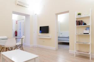 Una sala de estar con una mesa y un televisor en una pared. en Adama Apartamento Turístico, en Cáceres