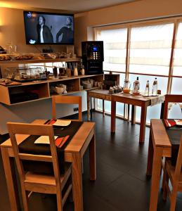 una cucina con tavoli e sedie in legno e una TV di Le 24 Hotel a Spa