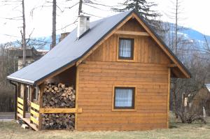 a log cabin with a pitched roof and a pile of logs at Domki na Wyrszczku in Istebna