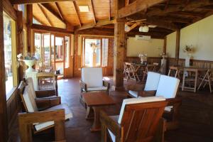 Habitación con sillas, mesas y ventanas de madera. en Un Lugar Hotel Cabañas en Eldorado