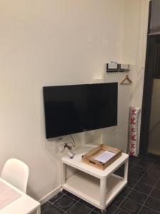 een flatscreen-tv aan een muur met een witte tafel bij Via Braschi Sessantotto in Cesena