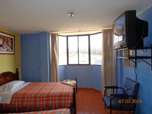 a bedroom with a bed and a tv and a window at Hostal Miraflores Cayambe in Cayambe