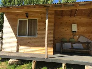 a wooden cabin with a porch and a window at Monte Campamento Hostel in Puerto Bertrand