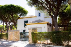 una casa bianca con cancello e alberi di Coreto's Village a Praia Verde
