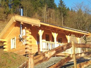 eine Blockhütte im Wald mit einer Veranda in der Unterkunft Der Nesselbacher in Schmallenberg