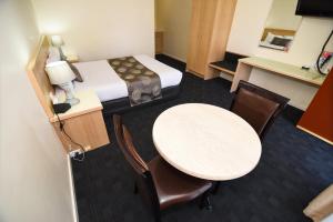 a hotel room with a bed and a table and chairs at Sandown Heritage Motel in Noble Park