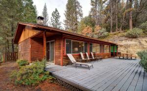 a cabin with a deck with chairs and an umbrella at 17A Longview in Wawona