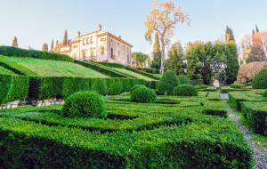 um jardim em frente a uma casa com arbustos em Villa Betteloni Valpolicella Suites em San Pietro in Cariano