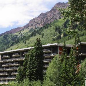 a large building with trees in front of a mountain at The Lodge at Snowbird in Alta