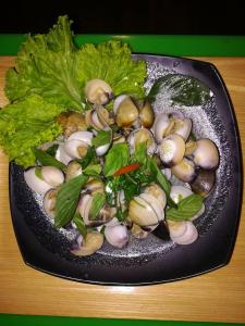 a plate of mushrooms and greens on a table at Chomlay Room & Restaurant in Ko Lanta