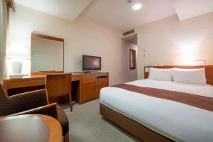 Pokój hotelowy z łóżkiem, biurkiem i lustrem w obiekcie Meitetsu Grand Hotel w mieście Nagoja