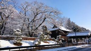 a house covered in snow next to a fence at Hotel Wakasa in Ashikaga