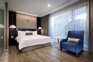 a bedroom with a large bed and a blue chair at Hua Hotel in Tainan