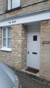 ein Gebäude mit einer weißen Tür und einem Schild darauf in der Unterkunft The Shop By Treetop Property in Cirencester