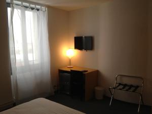 Habitación con cama, lámpara y TV. en Au Boeuf Rouge, en Crassier
