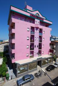 un edificio rosa con un coche aparcado delante de él en Hotel Clara, en Tortoreto Lido
