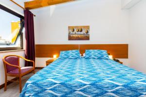 een slaapkamer met een bed met een blauw dekbed en een stoel bij Hotel Adria in Mestre