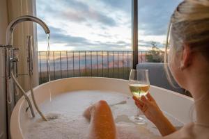a woman in a bath tub with a glass of wine at Hotel El Balcon de las nieves in La Zubia
