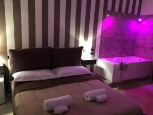 1 dormitorio con cama y bañera con luces moradas en Alba Camere, en Palermo