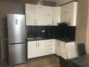 a kitchen with white cabinets and a stainless steel refrigerator at Haystack Bakuriani in Bakuriani