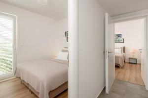 a white bedroom with a bed and a window at Belado Residence Bol in Bol