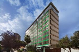 a tall office building with green windows at Haifa Bay View Hotel in Haifa