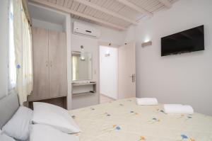 a white bedroom with a large bed and a television at Pension Elena in Agia Anna Naxos