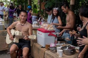 a man playing a guitar in front of a group of people at Soothing Stay Backpackers Inn in T'ien-wei