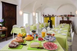 a long dining room with green tables with food on them at Hotel Garni Maggia in Coglio