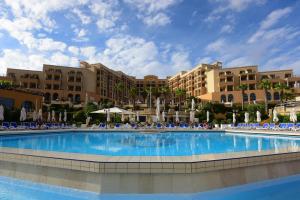 a large swimming pool with blue chairs and fountains at Corinthia St George's Bay in St. Julianʼs