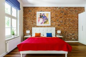 a bedroom with a red bed with a brick wall at Sanhaus Apartments in Sopot